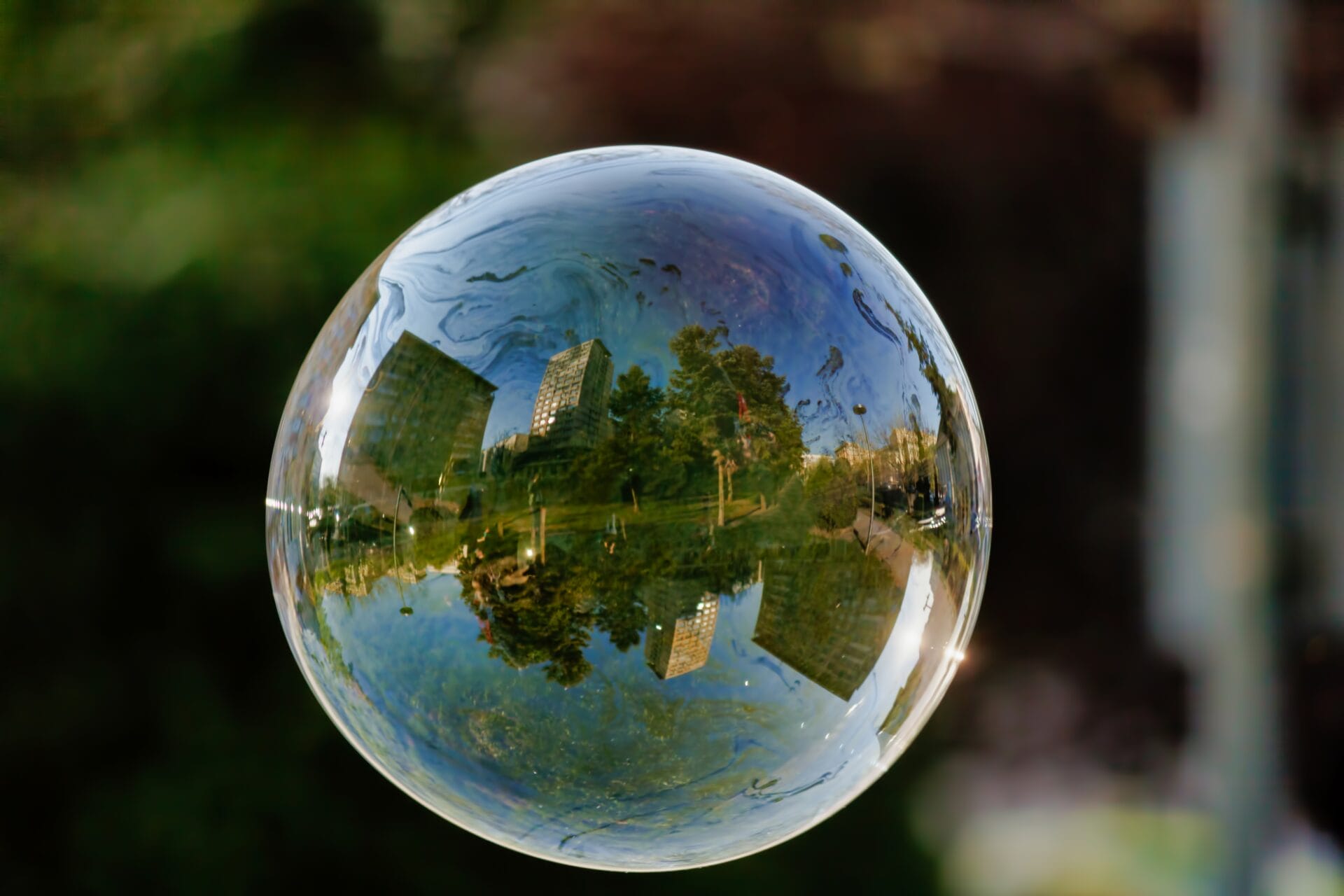 Soft focus of a bubble with reflection of city buildings and trees on it | ION SENSE